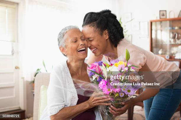 woman giving mother bouquet of flowers - woman giving flowers stock-fotos und bilder