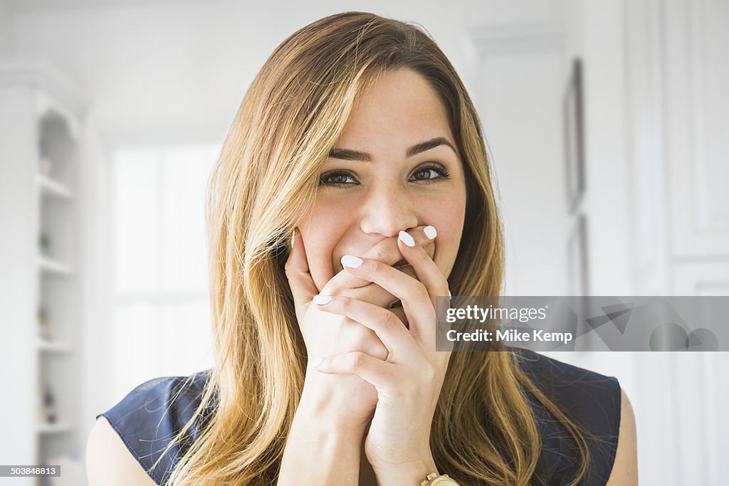 Mixed race woman covering her mouth at home