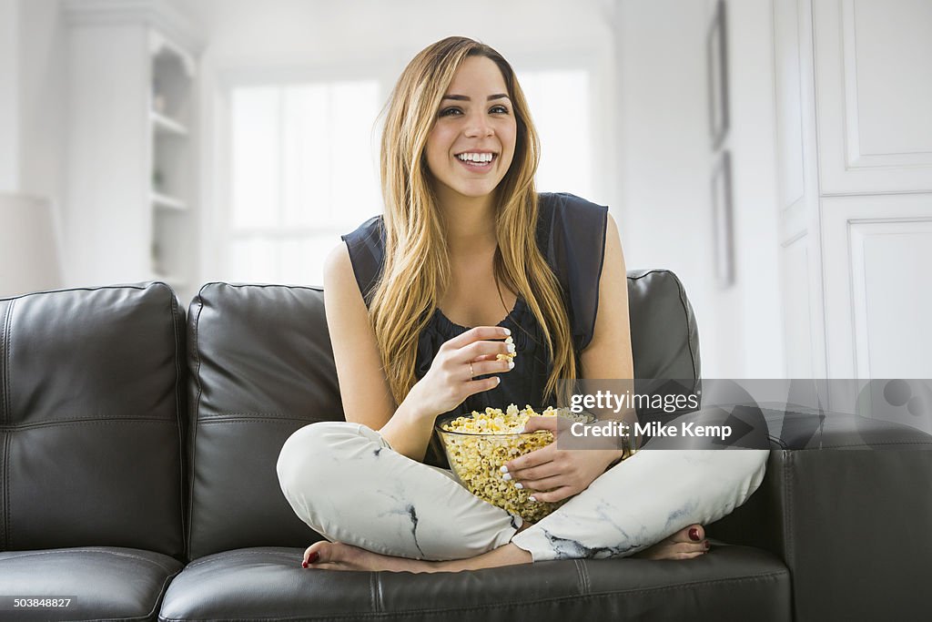 Mixed race woman watching television on sofa