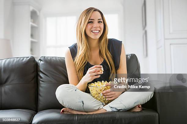 mixed race woman watching television on sofa - stressed young woman sitting on couch stock pictures, royalty-free photos & images