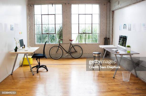 bicycle and desks in modern office - kleines büro stock-fotos und bilder