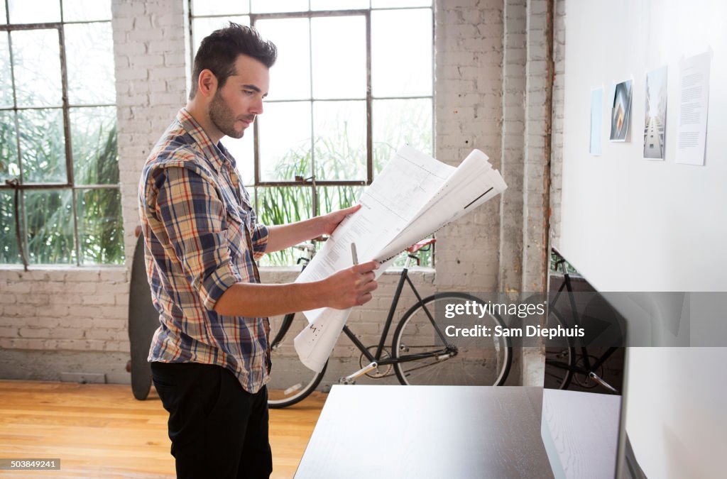 Caucasian architect reading blueprints in office