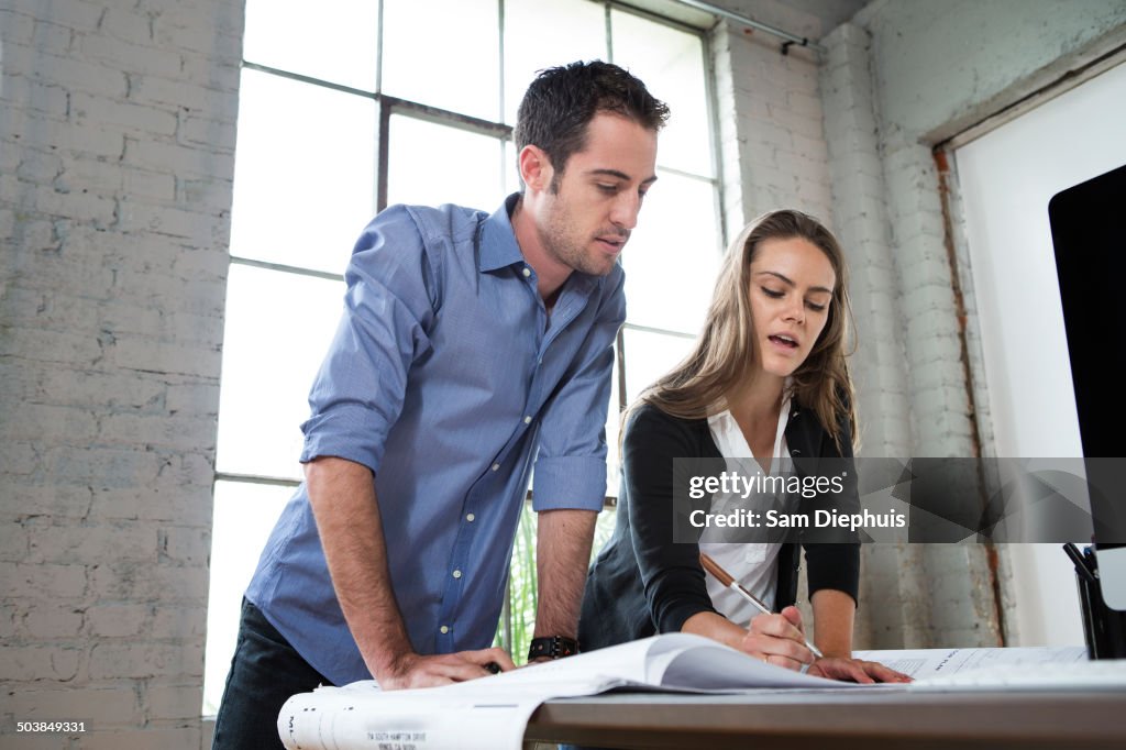 Caucasian architects designing blueprints in office