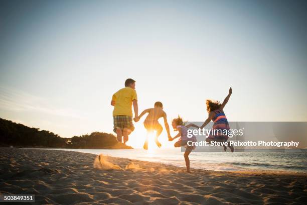 family jumping for joy on beach - leap day stockfoto's en -beelden