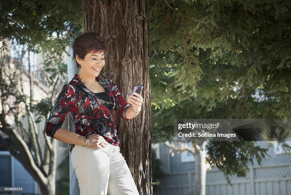 Hispanic woman using cell phone outdoors