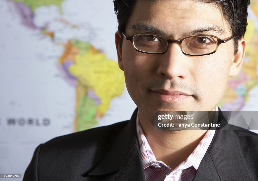 Mixed race businessman standing by world map