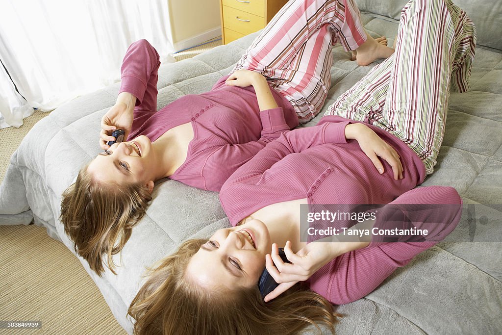 Caucasian twin teenage girls talking on cell phones