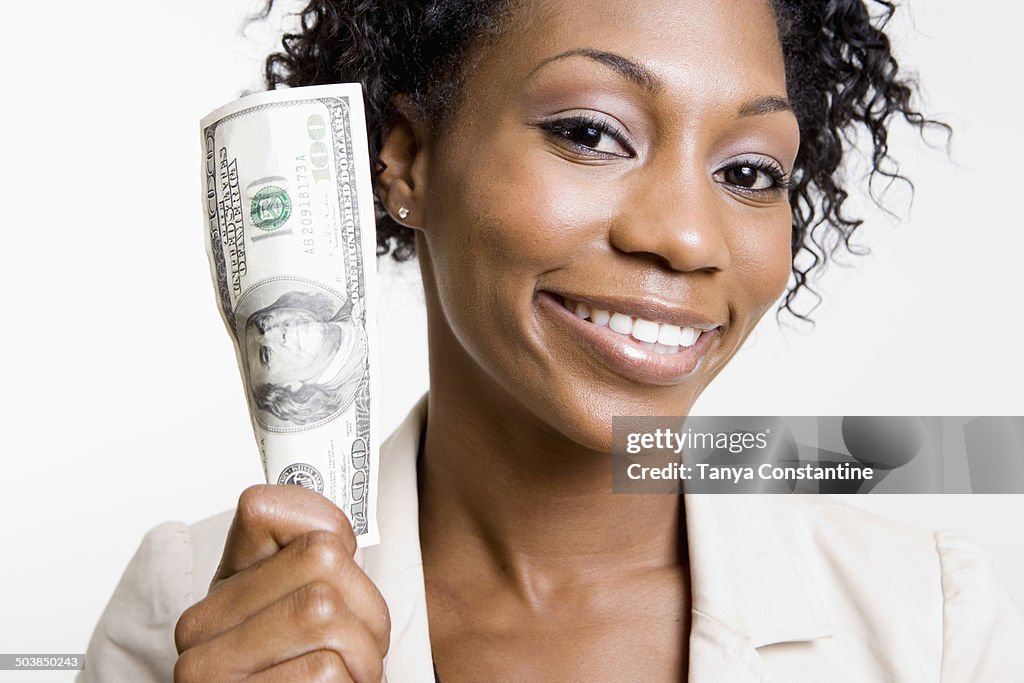 African American woman holding hundred dollar bill