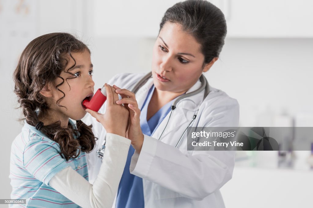 Doctor helping patient use inhaler in office