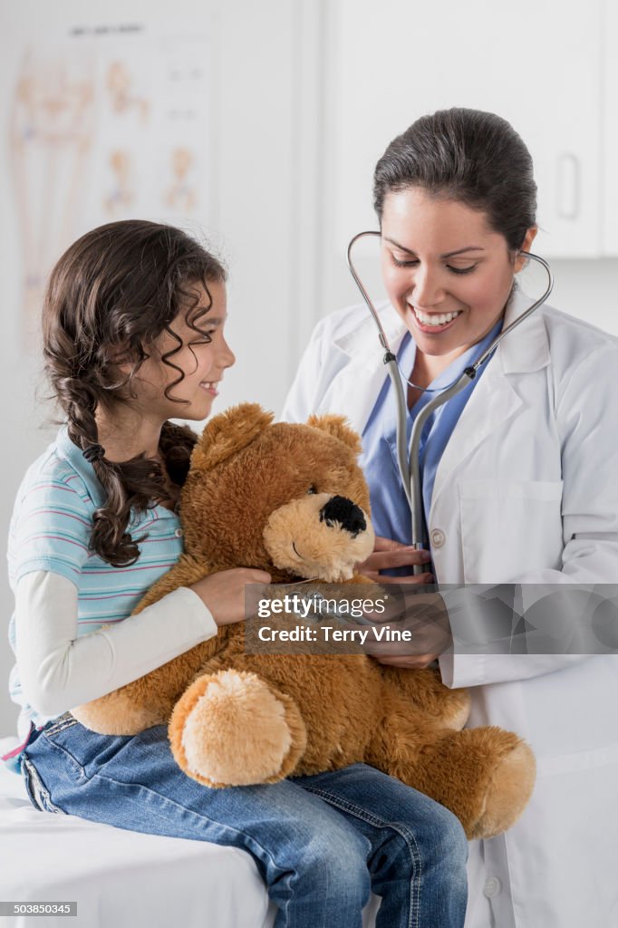 Doctor checking teddy bear's heart beat for patient