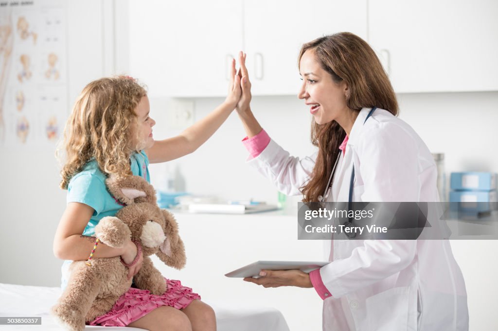 Doctor and patient high fiving in office