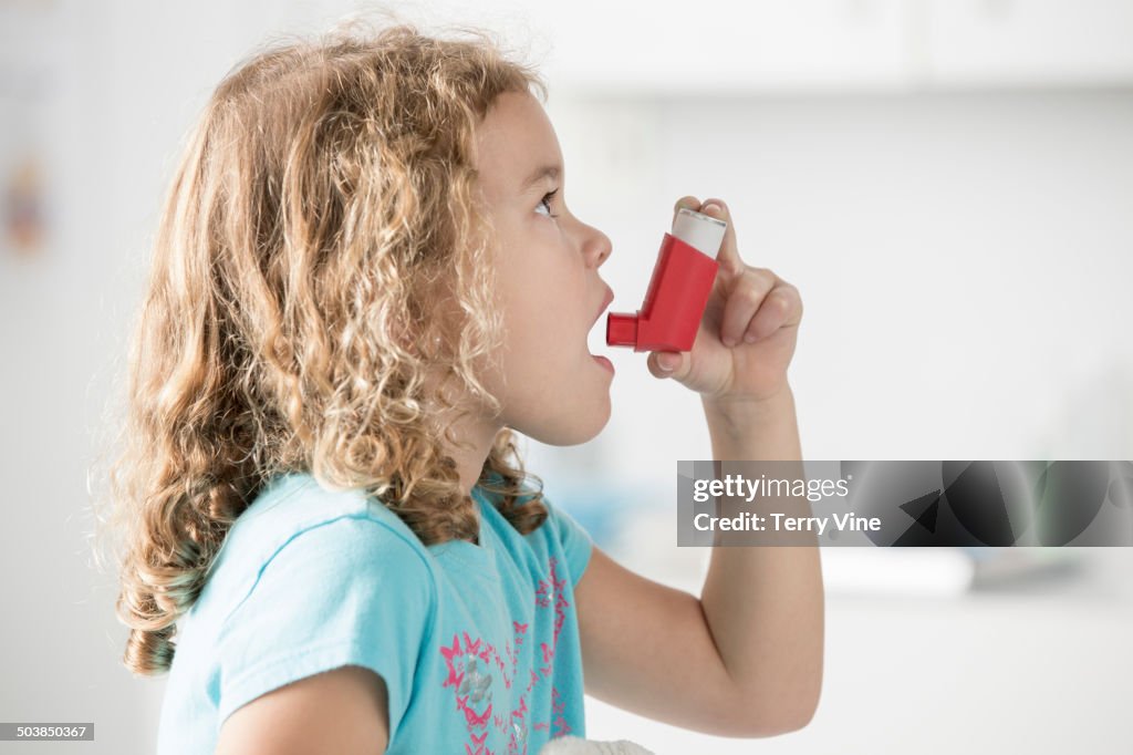 Caucasian girl using inhaler in doctor's office