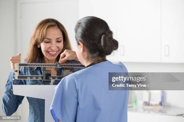 nurse weighing patient in office - doctor's office scale stock pictures, royalty-free photos & images