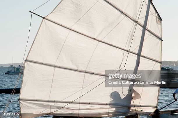 sail hoisting silhouette - sailboat silhouette stock pictures, royalty-free photos & images