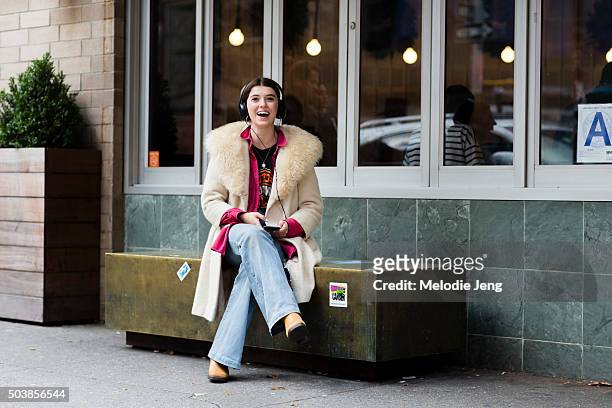 Elise Hoggard wears a vintage off-white coat with a fur collar, a cerise button-up shirt, Harley-Davidson t-shirt, light flared jeans, brown suede...