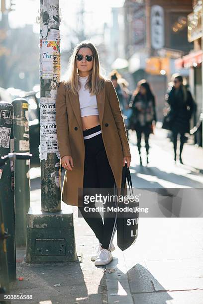 Sam Nirenberg of the mobile app Spring wears aviator sunglasses, a Zara camel coat, white American Apparel crop top, black Adidas pants, white canvas...