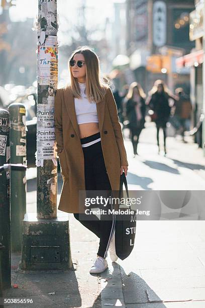 Sam Nirenberg of the mobile app Spring wears aviator sunglasses, a Zara camel coat, white American Apparel crop top, black Adidas pants, white canvas...