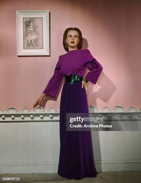 Canadian-born American actress and singer Deanna Durbin wearing a purple evening gown, 1946. On the wall behind her is a Degas sketch of a ballerina.