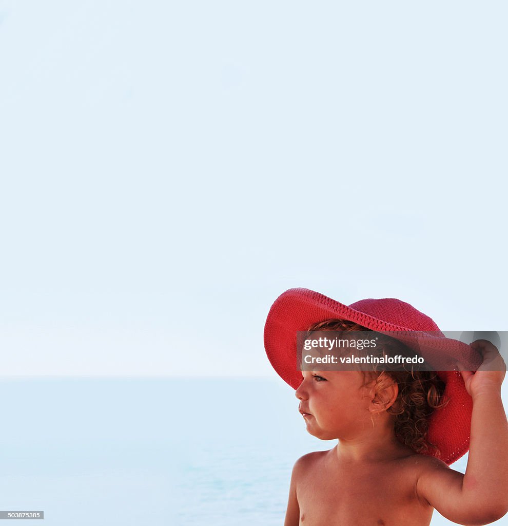 Girl (2-3) by sea in red hat