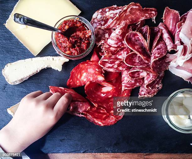 human hand reaching for charcuterie and cheese board - charcuterie stockfoto's en -beelden