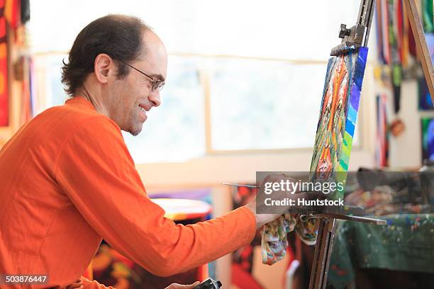 man with aspergers painting in his art studio - autismus stock pictures, royalty-free photos & images