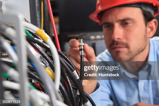 Network engineer holding BNC cable connection at patch panel Network engineer holding BNC cable connection at patch panel