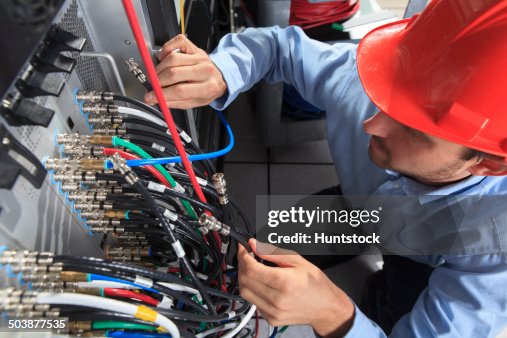 Network engineer holding BNC cable connection at patch panel Network engineer holding BNC cable connection at patch panel
