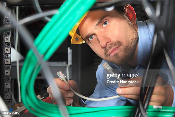 network engineer examining patch cable under patch panel - tomada de ligação à rede imagens e fotografias de stock