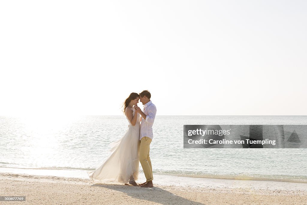 Young wedding couple embracing on beach by the sea