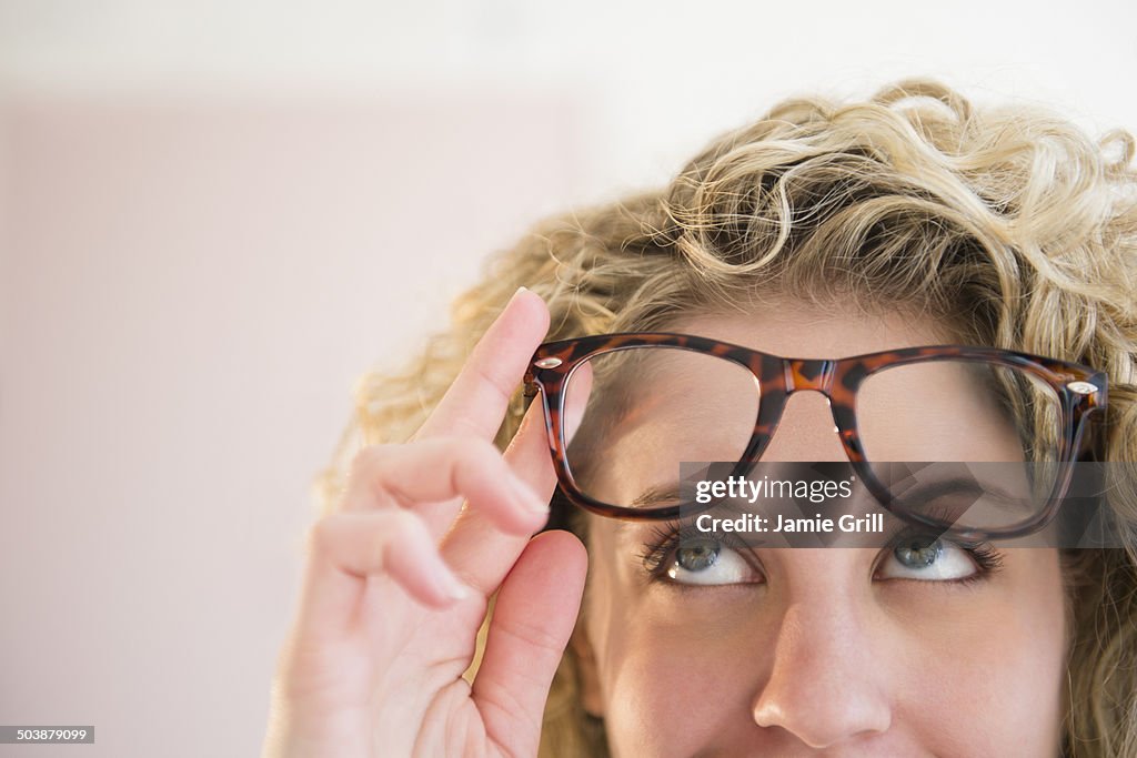 Woman wearing glasses, looking up in thought