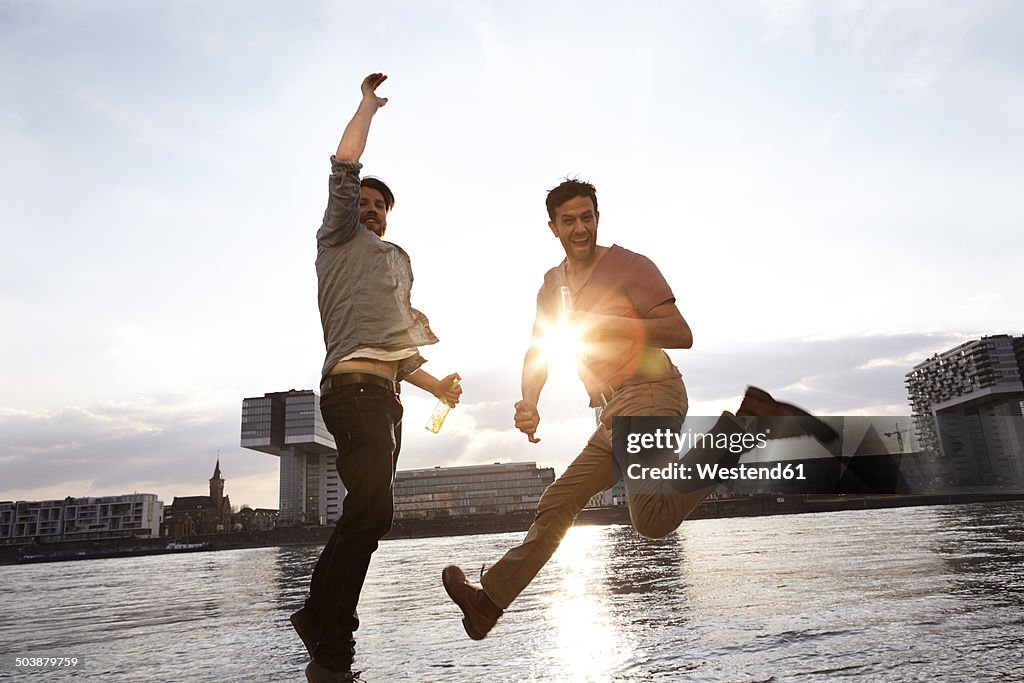 Two enthusiastic with beer bottles on riverbank