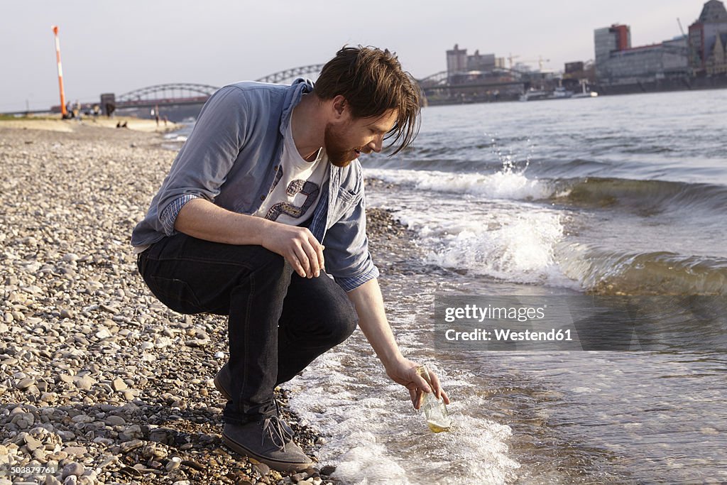 Man with beer bottle at river