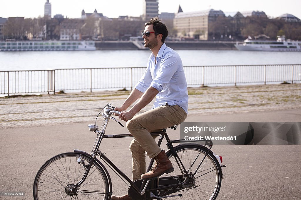 Man riding bicycle on riverbank