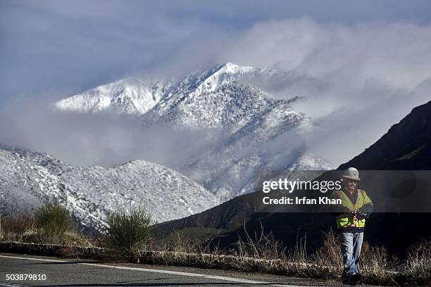 Snow covered Mt. Baldy shines in morning light behind LA county surveyors working on Mt. Baldy Road.