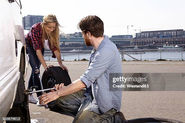 smiling couple changing car tyre at minivan - alter rhein stock pictures, royalty-free photos & images