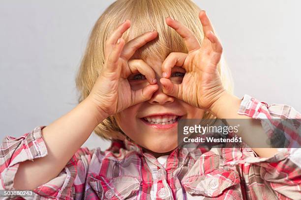 portrait of little girl shaping glasses with fingers - child with binoculas stockfoto's en -beelden