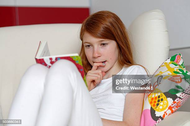 girl sitting on sofa reading a book - girl sitting with legs open stock pictures, royalty-free photos & images