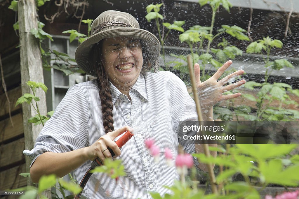 Young woman splashing with water in garden