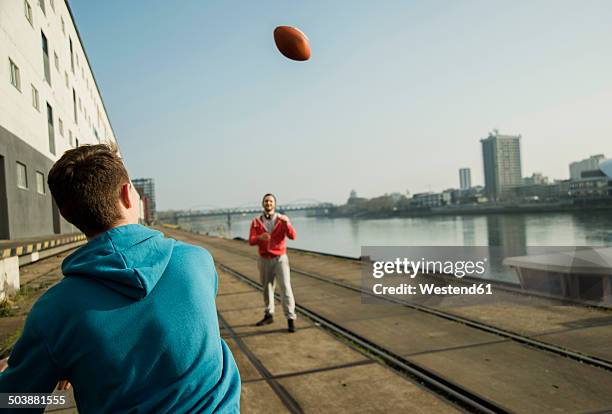 young man and teenager playing football by the riverside - boy throwing stockfoto's en -beelden