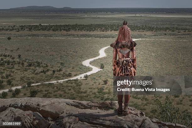 himba woman watching an empty road - opuwo tribe foto e immagini stock