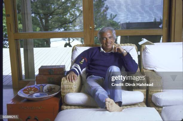 Fashion Designer Ralph Lauren relaxed and sitting on couch in his home.