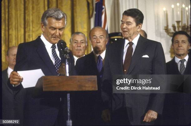 Australian PM Robert J. L. Hawke speaking at podium with others standing by including: WH Chief of Staff Donald T. Regan, State Secy. George P....