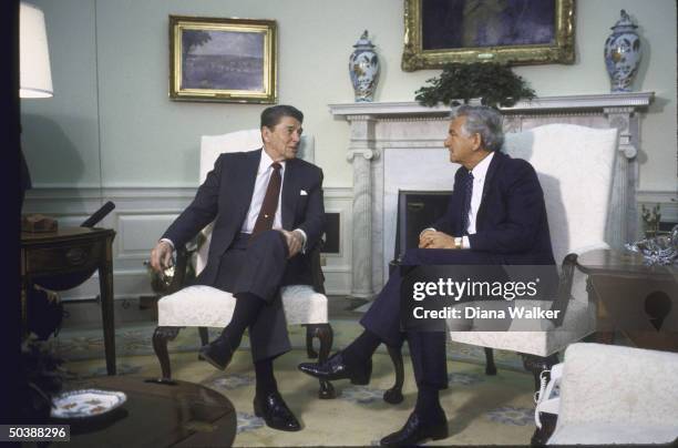 Pres. Ronald W. Reagan seated, talking with Australian PM Robert J. L. Hawke in Oval Office.