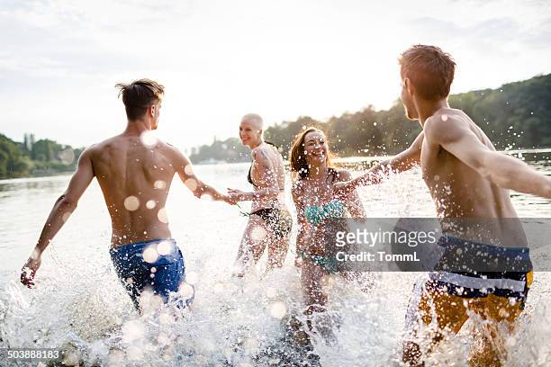 young couples running in lake - beach fun stock pictures, royalty-free photos & images