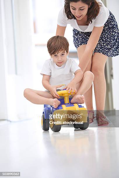 mother pushing daughter in toy car - skimpy girls stock pictures, royalty-free photos & images