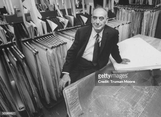 World's Fair Corp. Pres. Robert Moses sitting with blueprints for various fair buildings.