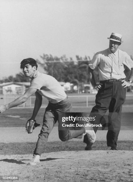 Yankee relief pitcher in the 1930's Johnny Murphy , looking over John Poppas , an amateur trying out for the Mets.