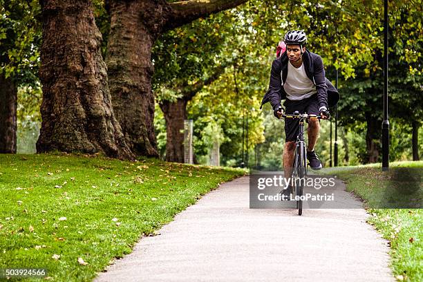 commuter cycling in the park going at work in london - london bikes stock pictures, royalty-free photos & images