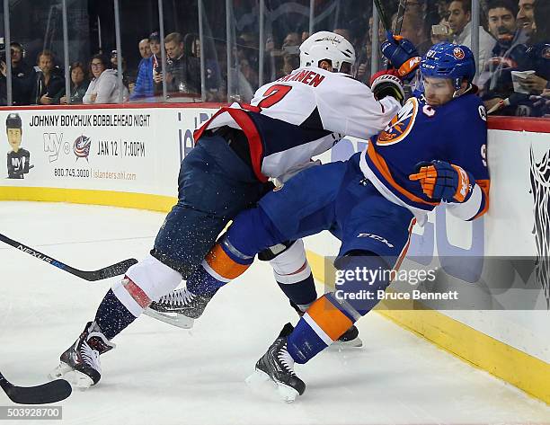 John Tavares of the New York Islanders is hit into the boards by Matt Niskanen of the Washington Capitals during the second period at the Barclays...