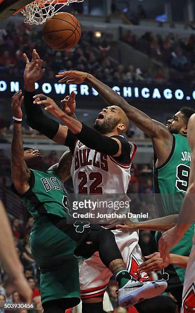 Taj Gibson of the Chicago Bulls is fouled while shooting between Isaiah Thomas and Amir Johnson of the Boston Celtics at the United Center on January...